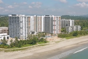 A high-rise residential building with multiple balconies, situated near a beach. - Deluxe Holiday Studio Suite @ Timurbay w/ Seaview (Kuantan)