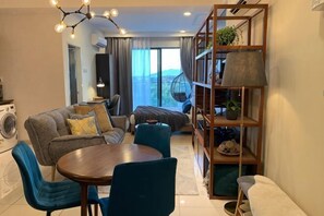 A modern living room with a sofa, chairs, a round table, and a bookshelf. - Deluxe Holiday Studio Suite @ Timurbay w/ Seaview (Kuantan)