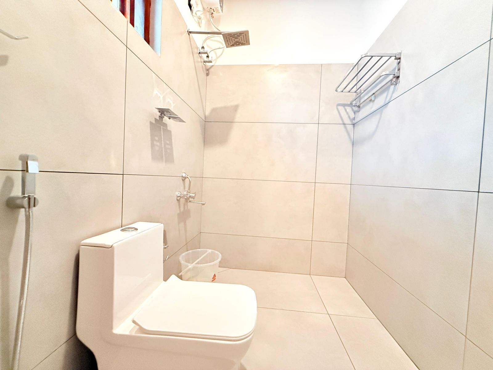Een kleine, moderne badkamer met toilet, douche en een handdoekhouder.