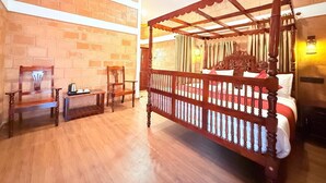 A spacious room with a large bed, wooden furniture, and a brick wall. - CREDIBLE HERITAGE RESORT (Varkala)