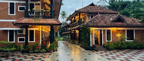 A traditional building with a tiled roof, a central courtyard with a checkered floor, and surrounding greenery.