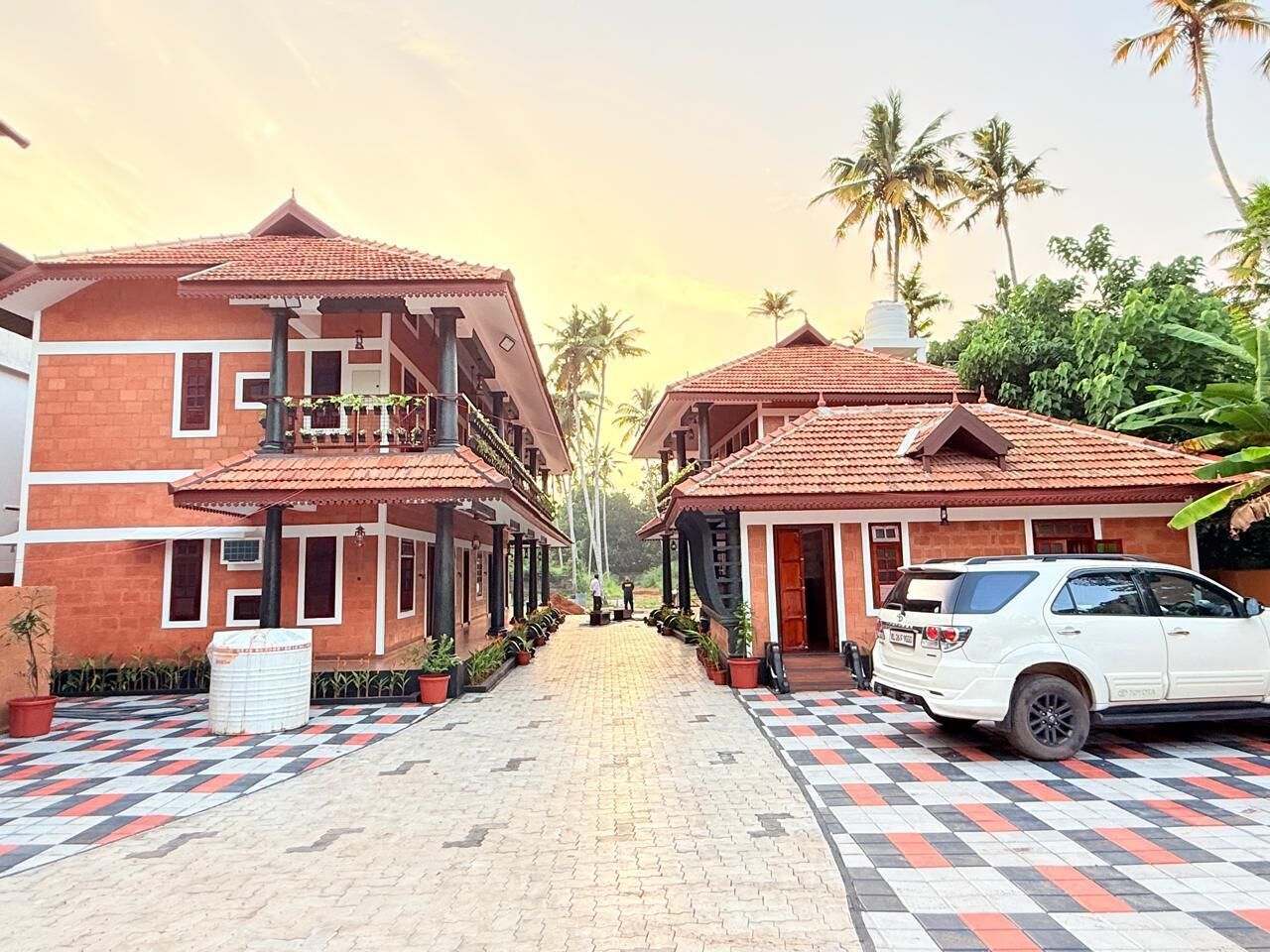 A hotel with a checkered pavement, two-story buildings, and a white car parked in front.