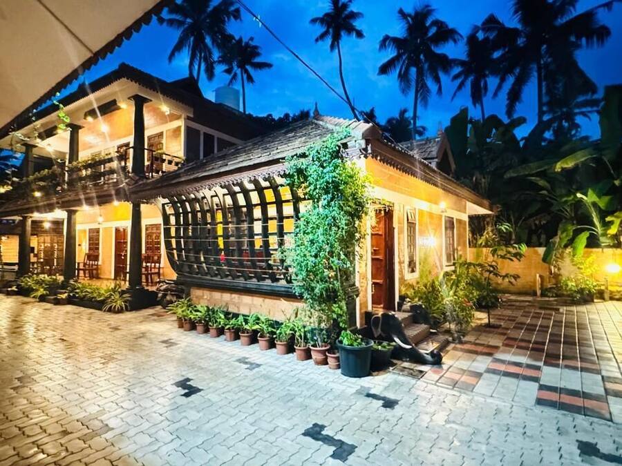 Una casa tradicional con un patio empedrado, plantas en macetas y una entrada bien iluminada.