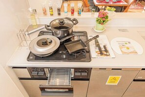 Une cuisine équipée d’une cuisinière, de casseroles, d’une poêle et d’une planche à découper.