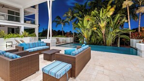 Un espace de détente extérieur moderne, avec des meubles en osier et une piscine.