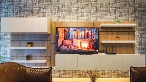 A modern living room with a flat-screen TV, leather sofas, and built-in shelving. - Baan PromTel , Luxury Villa close to Nimman, Resort Pool, 4BR (Chiang Mai)