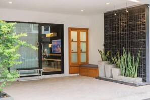 A modern interior with a sliding glass door, a wooden cabinet, and a black textured wall. - Baan PromTel , Luxury Villa close to Nimman, Resort Pool, 4BR (Chiang Mai)