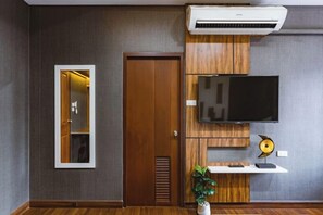 A room with a wooden door, a mounted TV, a mirror, and a potted plant. - Baan PromTel , Luxury Villa close to Nimman, Resort Pool, 4BR (Chiang Mai)