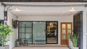 A modern building entrance with a glass door, a bench, and potted plants. - Baan PromTel , Luxury Villa close to Nimman, Resort Pool, 4BR (Chiang Mai)