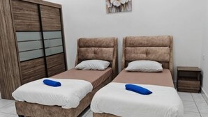 Una habitación con dos camas, un armario y una pequeña mesa.