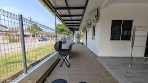 Un espacio al aire libre cubierto con una cerca metálica, una silla y una pequeña mesa.
