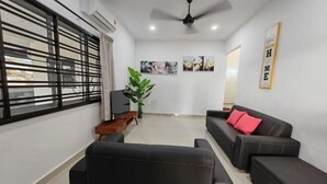 Una sala de estar con un sofá, un televisor, una planta y obras de arte en la pared.