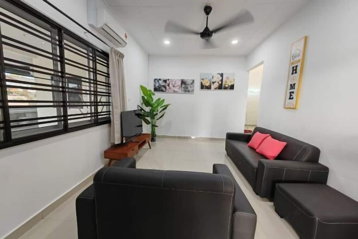 A living room with a sofa, a TV, a plant, and artwork on the wall.