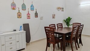 Un comedor con un armario blanco, una planta grande y adornos en la pared, incluyendo figuras de pájaros y una pequeña señal.