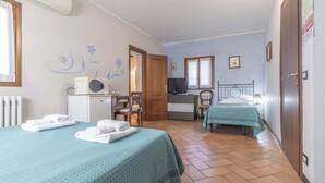A bedroom with two beds, a desk, a chair, a television, and a radiator. - 3T Tripla  Affitti Brevi Italia  · 3T Tripla - Affitti Brevi Italia (Modena)
