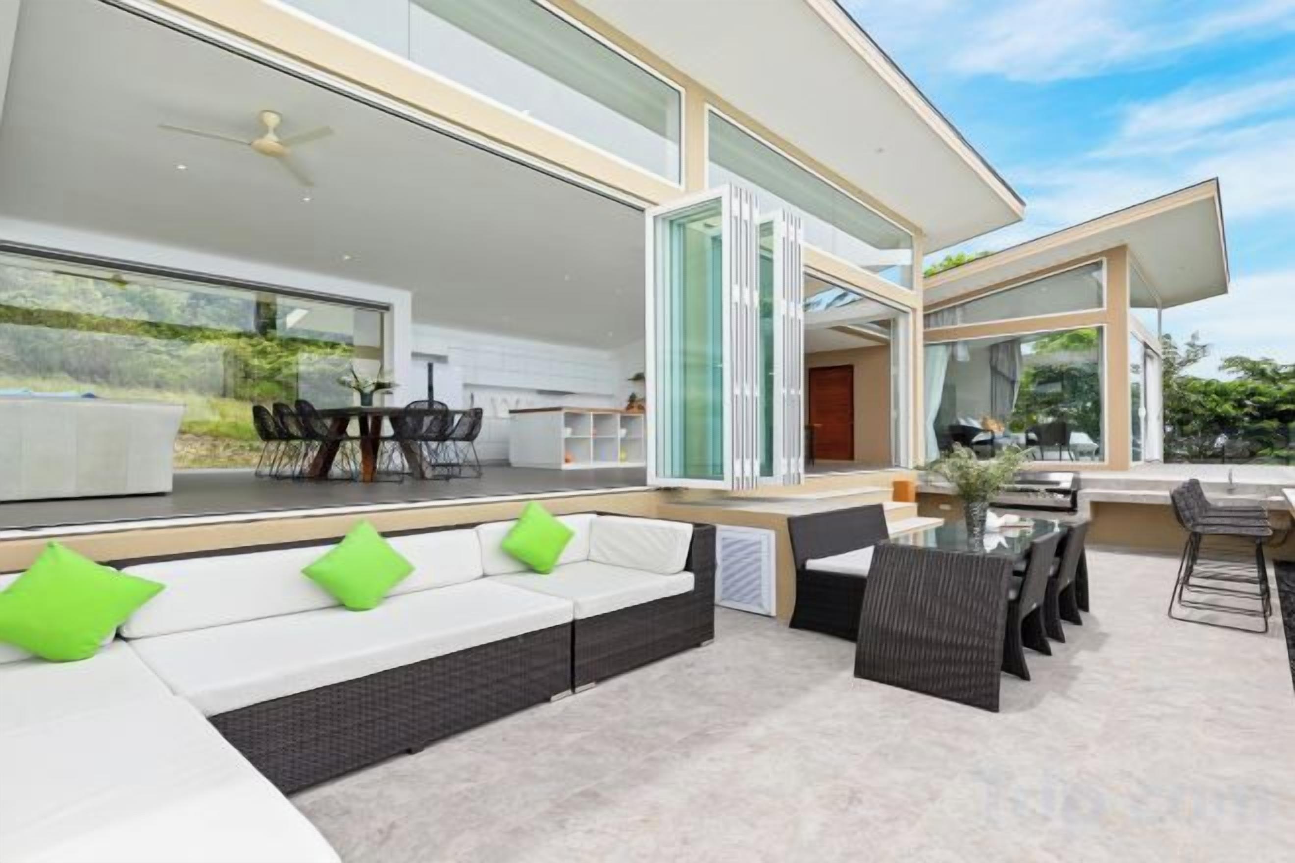 A modern outdoor living area with a seating arrangement, a dining table, and a bar area.
