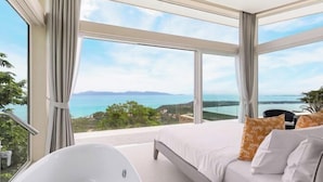 A modern bedroom with a large bed, a white bathtub, and a view of the ocean. - Villa Cabo: Hilltop Retreat with Panoramic Ocean Views (Koh Samui)