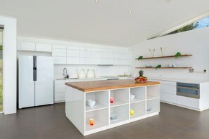 Una cocina moderna con armarios blancos, una isla de madera y electrodomésticos integrados.