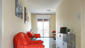 Een woonkamer met een bank, een salontafel en een tv-meubel met een plant.