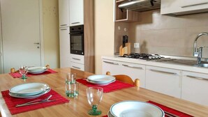 Een eethoek met een houten tafel, gedekt voor vier personen, inclusief borden, glazen en bestek.