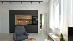 A modern kitchen with dark cabinets, a wooden countertop, and a built-in oven. - Steps from Palace & Riva - Old Town Pine (Split)