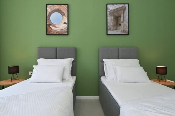 A hotel room with two beds, green walls, and framed pictures above the beds. - Steps from Palace & Riva - Old Town Pine (Split)