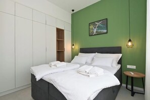 A bedroom with a bed, white towels, a green wall, a painting, and a pendant light. - Steps from Palace & Riva - Old Town Pine (Split)