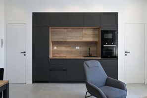 A modern kitchen with built-in appliances, a wooden countertop, and a gray chair. - Steps from Palace & Riva - Old Town Pine (Split)