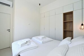 A hotel room with two beds, white linens, a wooden shelf, and a hanging light fixture. - Steps from Palace & Riva - Old Town Pine (Split)