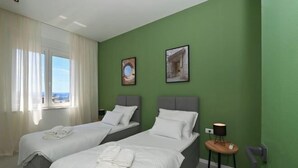 A hotel room with two beds, a window with curtains, a small table with a lamp, and two framed pictures on the wall. - Steps from Palace & Riva - Old Town Pine (Split)