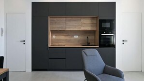A modern kitchen with dark cabinetry, a wooden countertop, and a built-in oven. - Steps from Palace & Riva - Old Town Pine (Split)