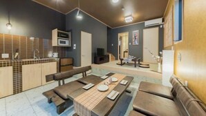 A modern kitchen with a dining area, including a table set for four, a bench, and a sofa. - Yadoya Negishi (Tokyo)