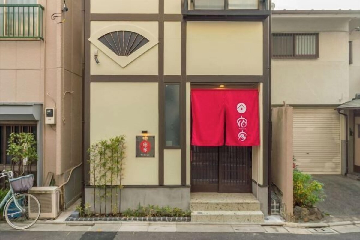 A building with a traditional Japanese architectural style, featuring a sliding door and a red awning with a logo.