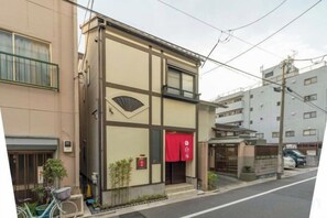 A building with a red awning, a bicycle parked outside, and a street in front. - Yadoya Negishi (Tokyo)