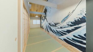 A corridor with tatami mat flooring, a traditional Japanese shoji screen, and a wave-patterned mural on the wall. - Yadoya Negishi (Tokyo)