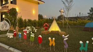 Een gebouw met een gele gevel en een rood dak, omringd door terrasjes en een tent.