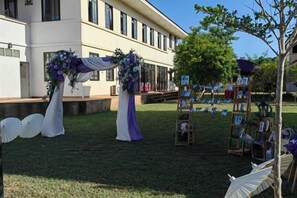 An outdoor wedding setup with a floral arch and a photo display. - New Blessing Home (Nan)