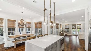 A spacious kitchen with a large island, wooden flooring, and pendant lighting. - Directly NEXT TO Camp WaterColor! 6-Seater LSV/Golf Cart & 4 Bikes Included! (Santa Rosa Beach)
