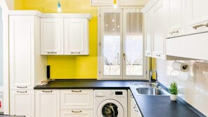 A modern kitchen with white cabinets, a washing machine, a sink, and a small potted plant. - Da Birba a Casinalbo · Da Birba a Casinalbo - Affitti Brevi Italia (Casinalbo)