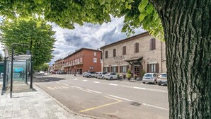 A street view with a row of parked cars, a bus stop, and a building with a sign that reads "La Cantina delle Arti." - Da Birba a Casinalbo · Da Birba a Casinalbo - Affitti Brevi Italia (Casinalbo)