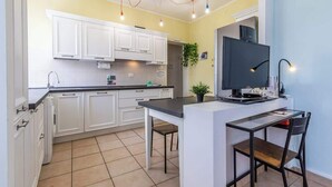 A kitchen with white cabinets, a black countertop, and a small island with a TV. - Da Birba a Casinalbo · Da Birba a Casinalbo - Affitti Brevi Italia (Casinalbo)