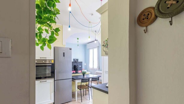 A modern kitchen with stainless steel appliances, a dining area with a table and chairs, and a hanging plant. - Da Birba a Casinalbo · Da Birba a Casinalbo - Affitti Brevi Italia (Casinalbo)