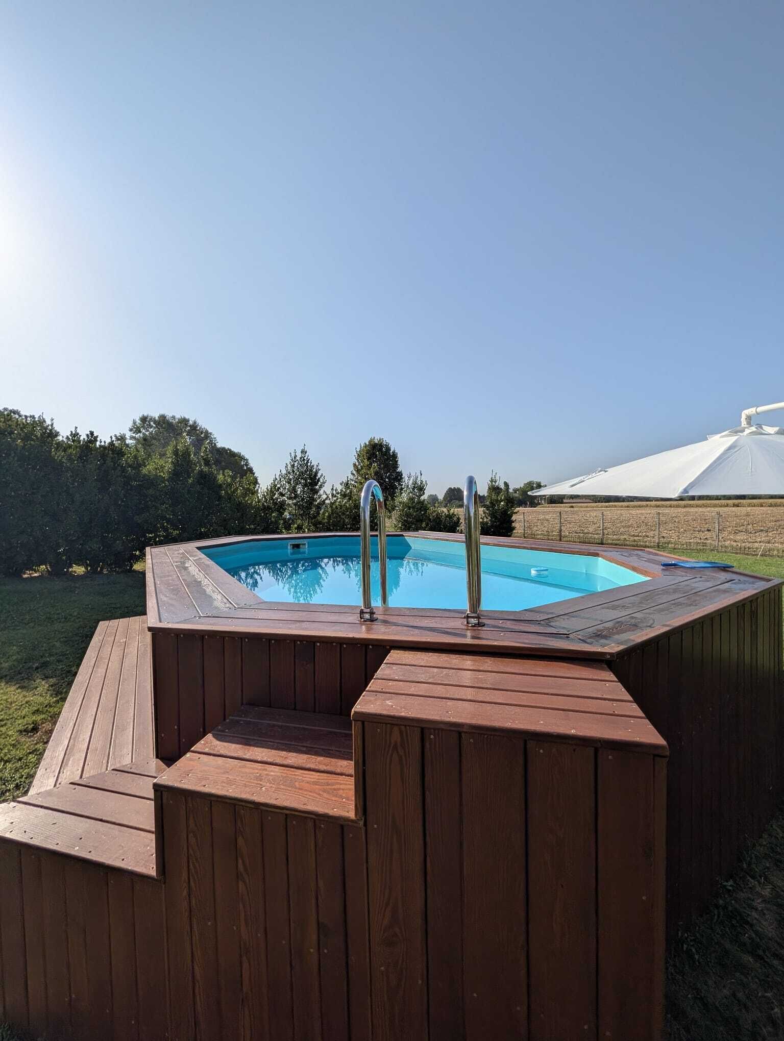 Un jacuzzi con terraza de madera y una piscina azul cristalina.