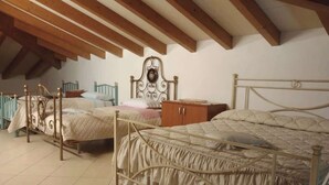 Een slaapkamer met twee bedden, houten balken in het plafond en betegelde vloer.