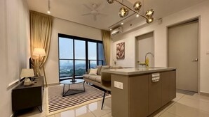 A modern hotel room with a sofa, a small table, a kitchen area, and a large window offering a city view. - KLCity & KLCC View Modern Style 2R2B - 6 pax (Kuala Lumpur)