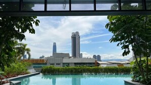 A swimming pool with a view of a city skyline, surrounded by greenery. - KLCity & KLCC View Modern Style 2R2B - 6 pax (Kuala Lumpur)