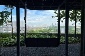A covered outdoor area with a swing, surrounded by greenery and a cityscape view. - KLCity & KLCC View Modern Style 2R2B - 6 pax (Kuala Lumpur)