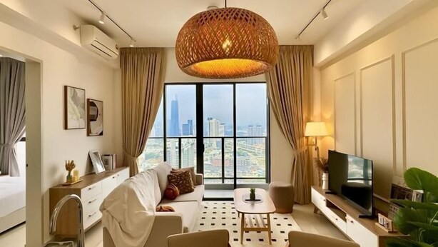 A modern hotel room with a large window offering a city view, a comfortable sofa, a dining table, a TV, and a decorative hanging light fixture. - KLCity & KLCC View Modern Style 2R2B - 6 pax (Kuala Lumpur)