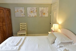 A bedroom with a bed, a chair, a wardrobe, and wall art. - Gardener's Cottage, Glen Lyon (Aberfeldy)