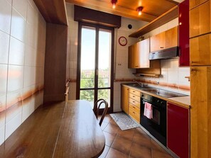 Een koelkast, een oven, een kookplaat, kookgerei, borden en bestek